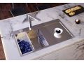 Alveus Inox kuhinjsko pomivalno korito vgrajeno v marmornat pult; v perforirani posodi so borovnice, na kovinski površini pa skodelica z jagodičevjem.